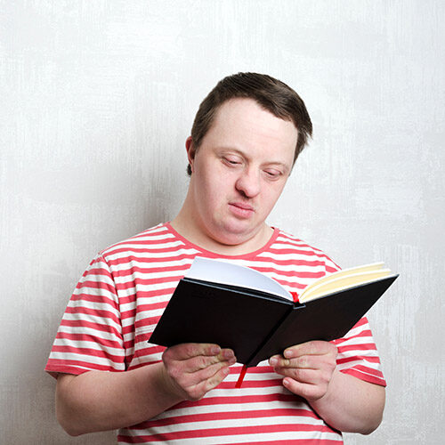 Young man with down syndrome reading a book